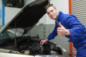 Portrait of mechanic gesturing thumbs up as he checks oil level of car